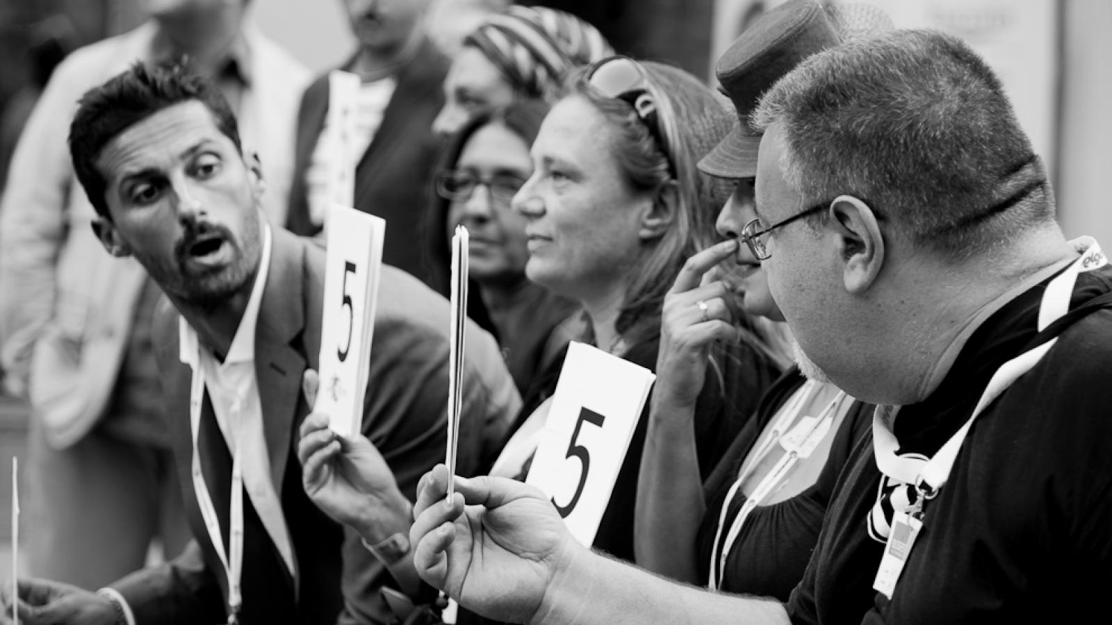 Mitglieder eine Jury halten zur Bewertung Schilder mit Zahlen vor sich