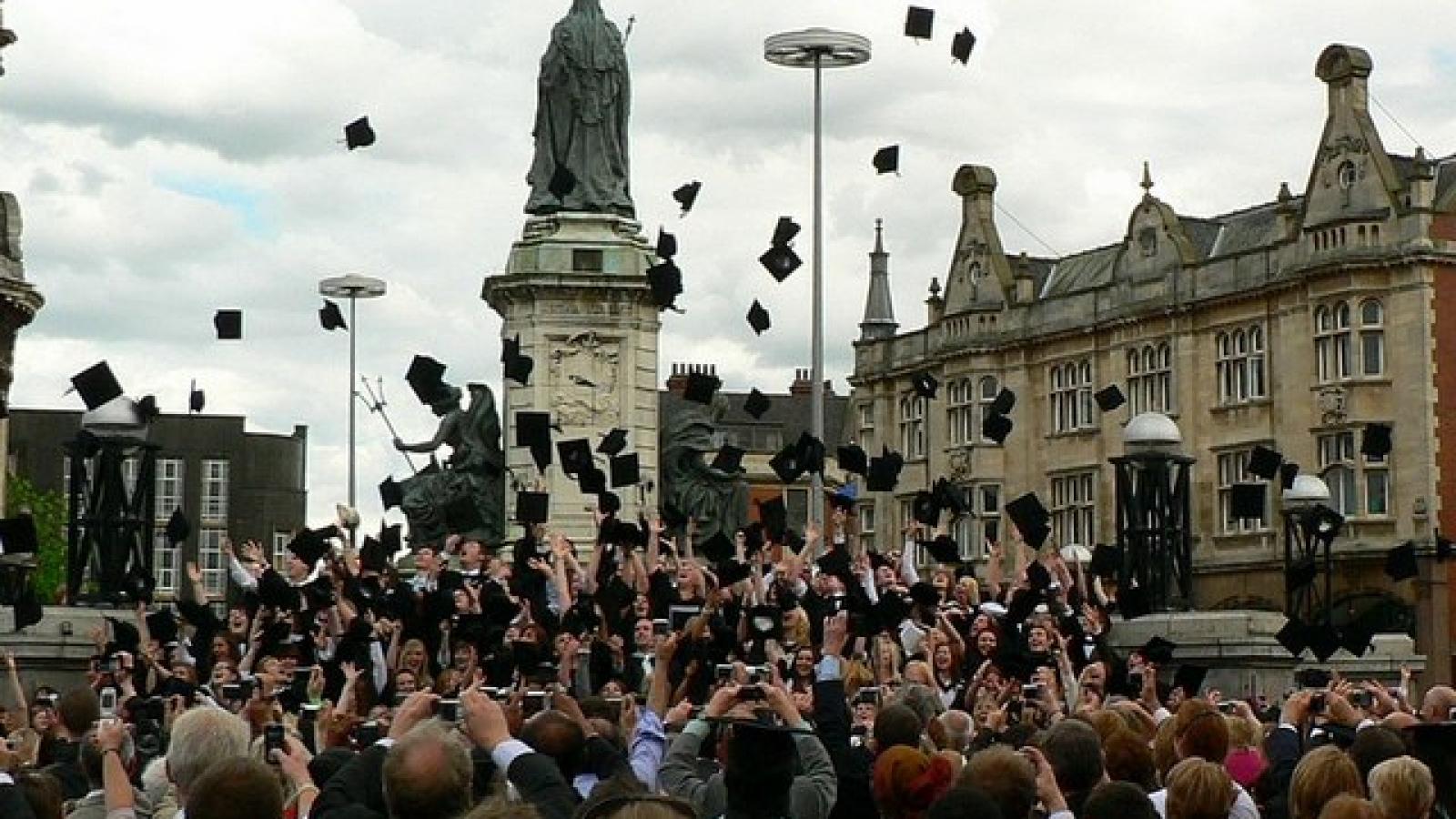 Universitätsabsolventen feiern ihren Abschluss indem sie gemeinsam ihre Hüte in die Luft werfen.