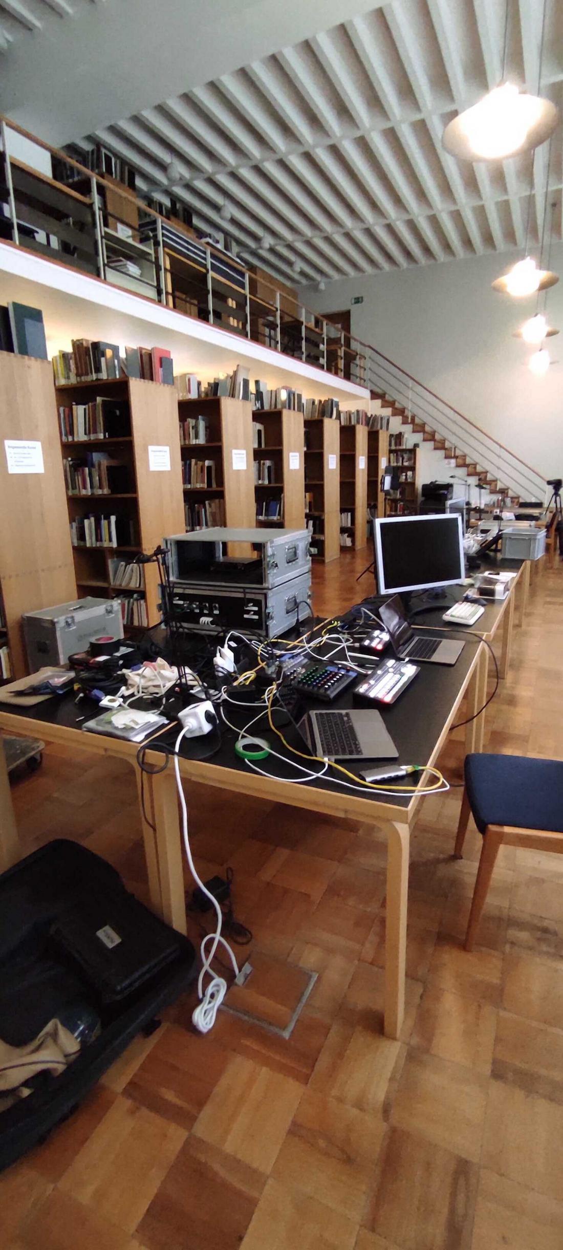 Foto der Bibliothek im MAKK mit zahlreichen Monitoren, Kabeln und anderer Technik, die für den Kick-Off aufgebaut wurde 