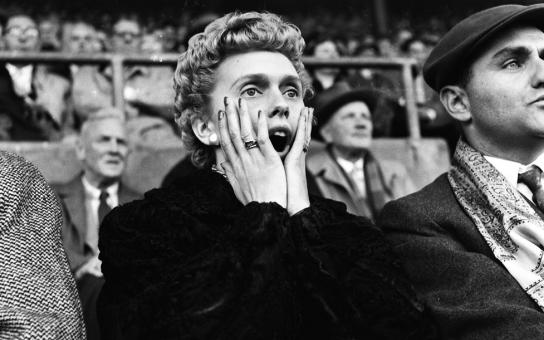 Frau hält sich gespannt bei einem Fußballspiel die Hände ans Gesicht